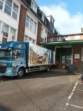Un camion bleu, à la caisse peinte d’une cathédrale, garé dans la cour d’un immeuble de brique