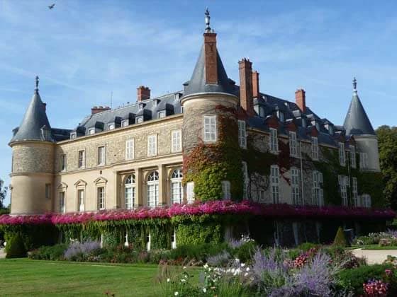 Le château de Rambouillet et ses tours, vu depuis un jardin fleuri