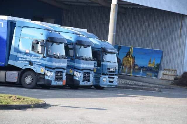 Trois tracteurs routiers aux couleurs de Transports Jumeau, alignés devant un entrepôt