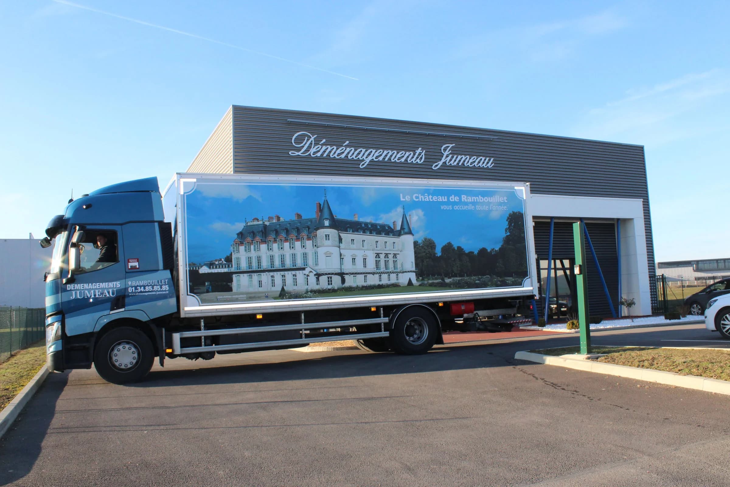Un camion habillé d’une vue du château de Rambouillet, devant un bâtiment au nom des Déménagements Jumeau