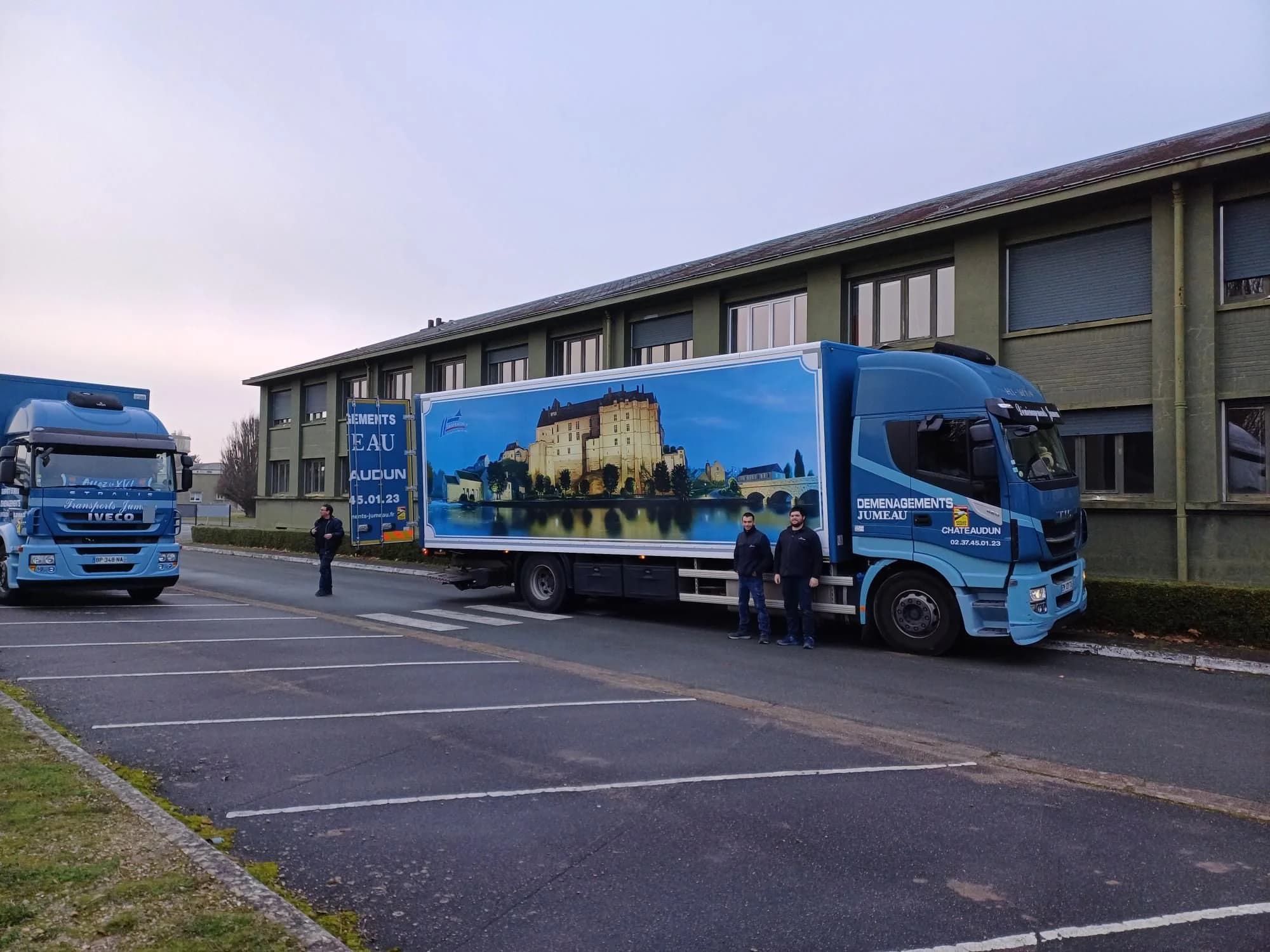 Un camion des Déménagements Jumeau habillé d’une peinture de château au bord de l’eau, garé devant un bâtiment de l’entreprise à Châteaudun