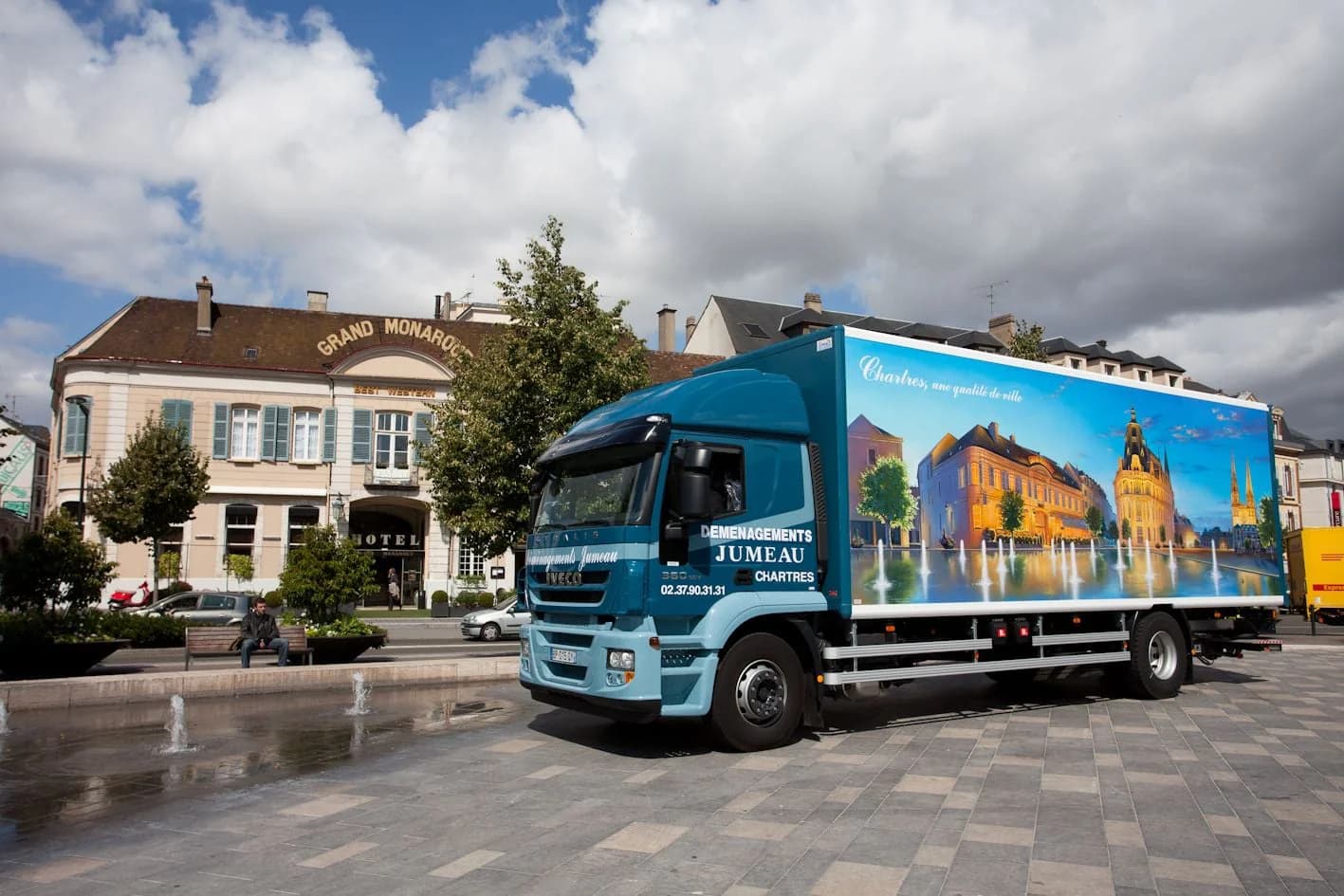 Un camion des Déménagements Jumeau sur une place pavée, devant l’hôtel du Grand Monarque