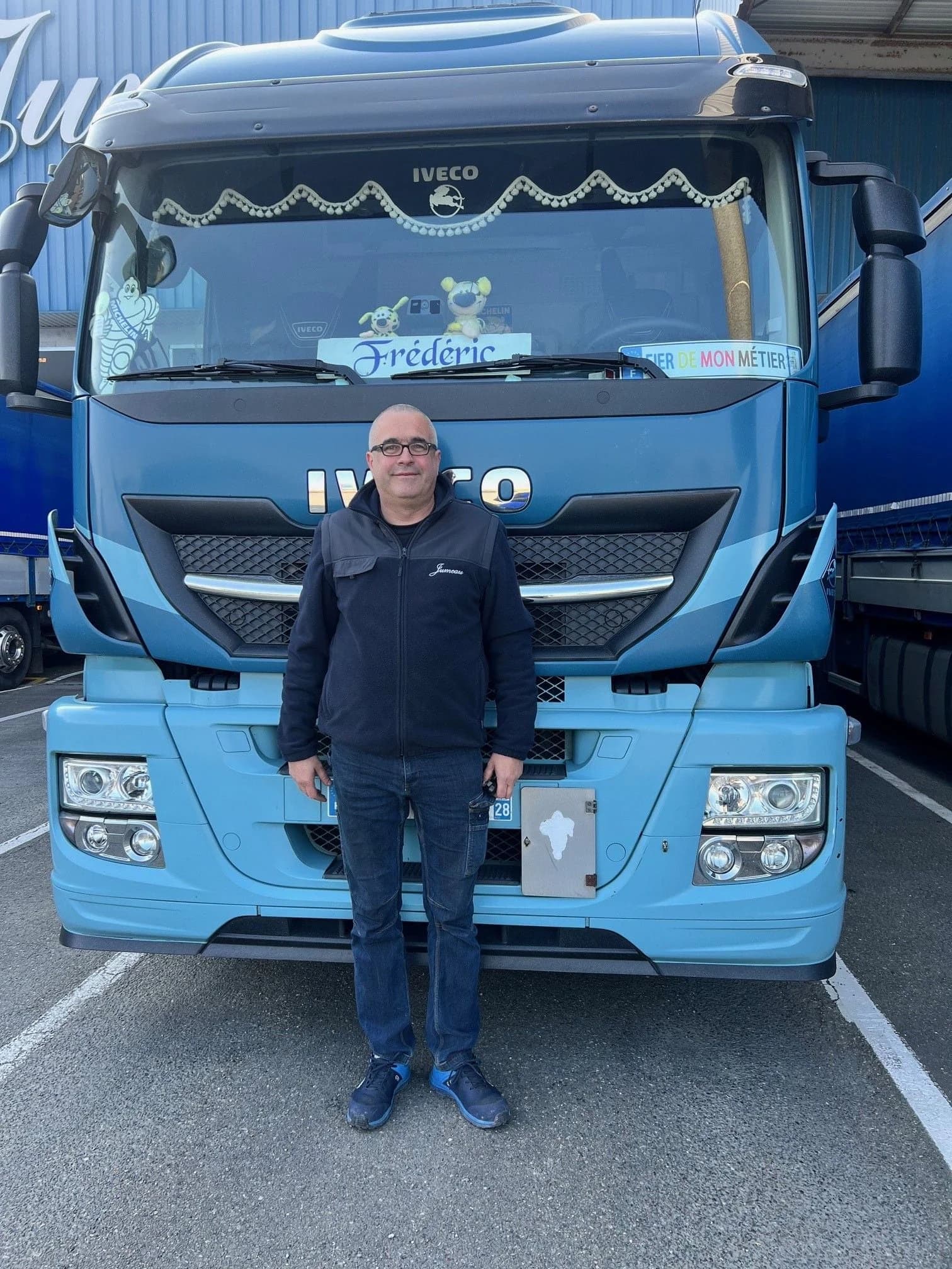 Un chauffeur des Transports Jumeau debout devant la cabine bleue de son camion