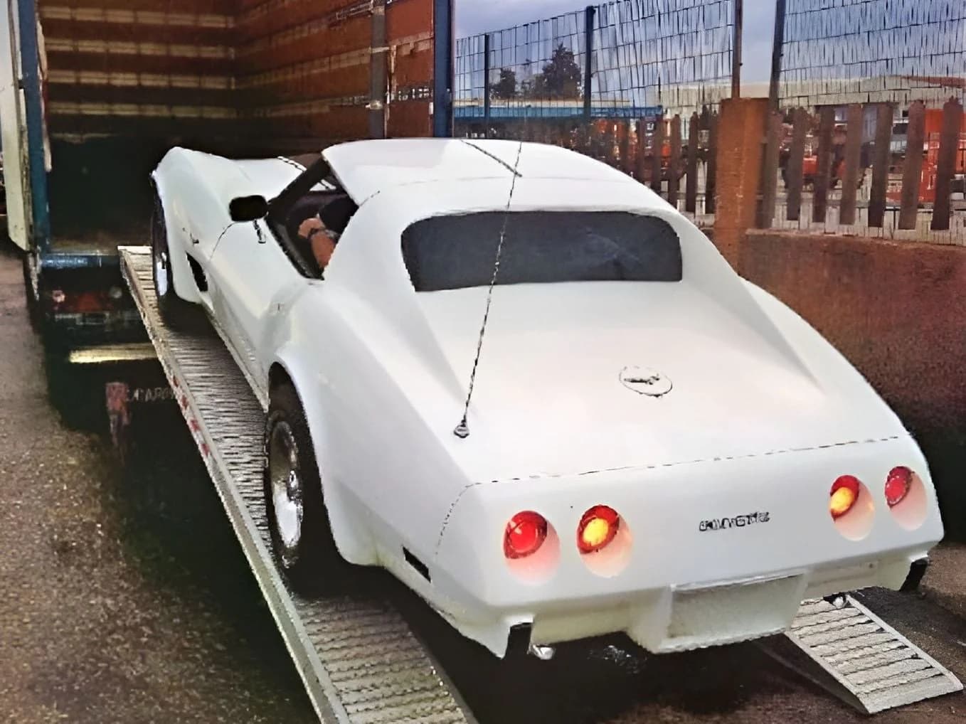 Une Chevrolet blanche monte par deux rampes dans la caisse d’un camion