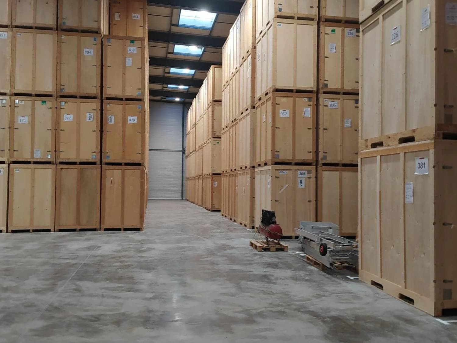 Une allée de garde-meubles bordée de caisses en bois empilées sur plusieurs niveaux