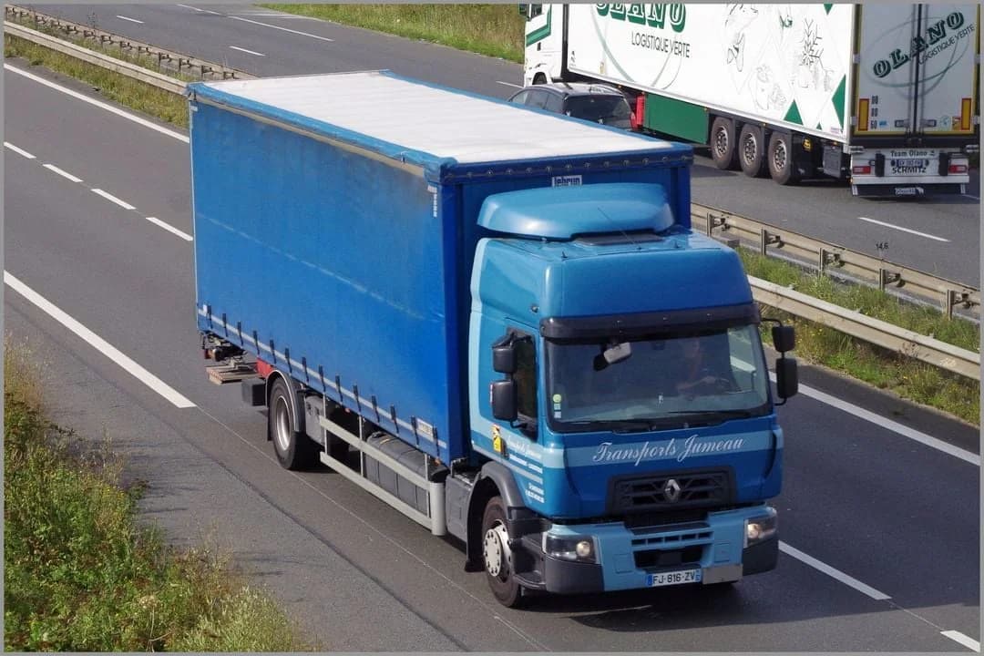 Un porteur bâché bleu des Transports Jumeau roule sur une voie rapide