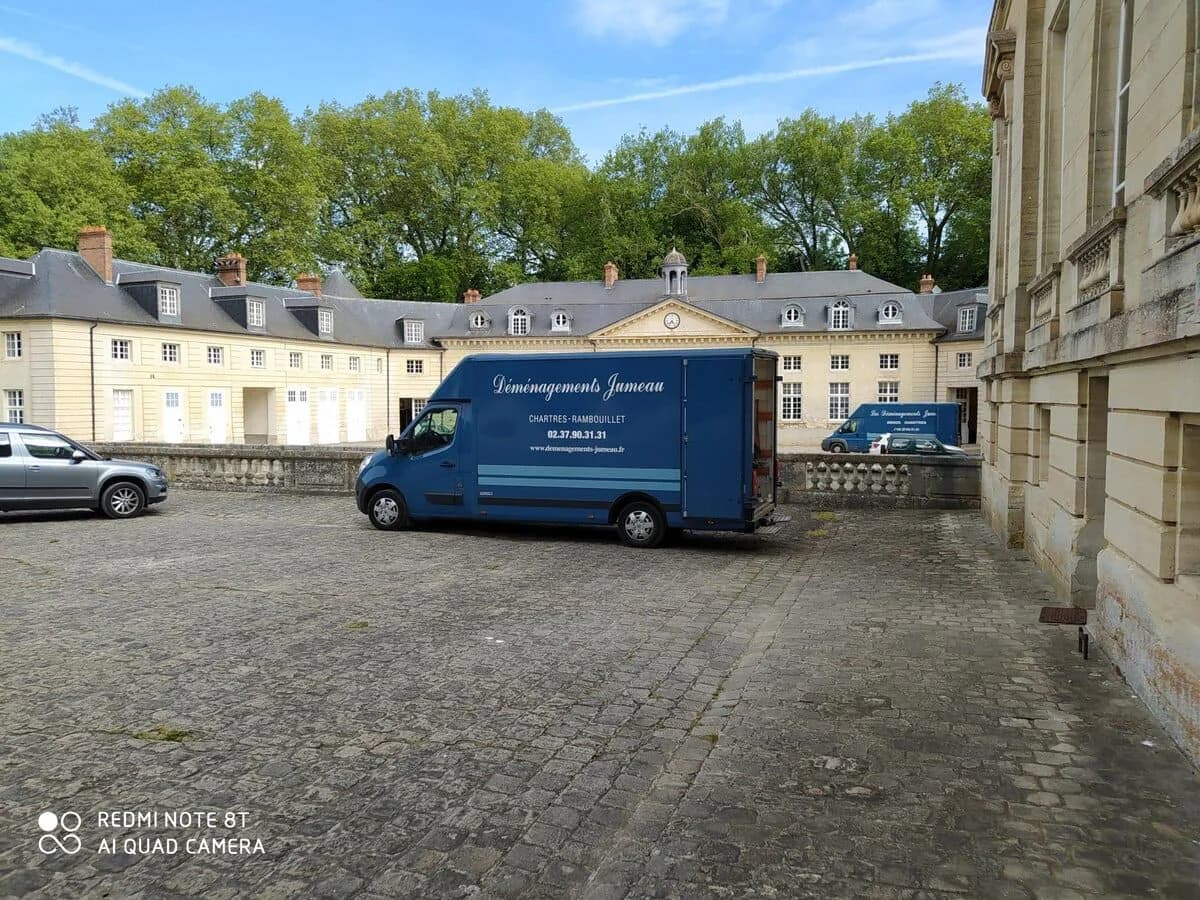 Un camion Déménagements Jumeau dans la cour pavée d’un château