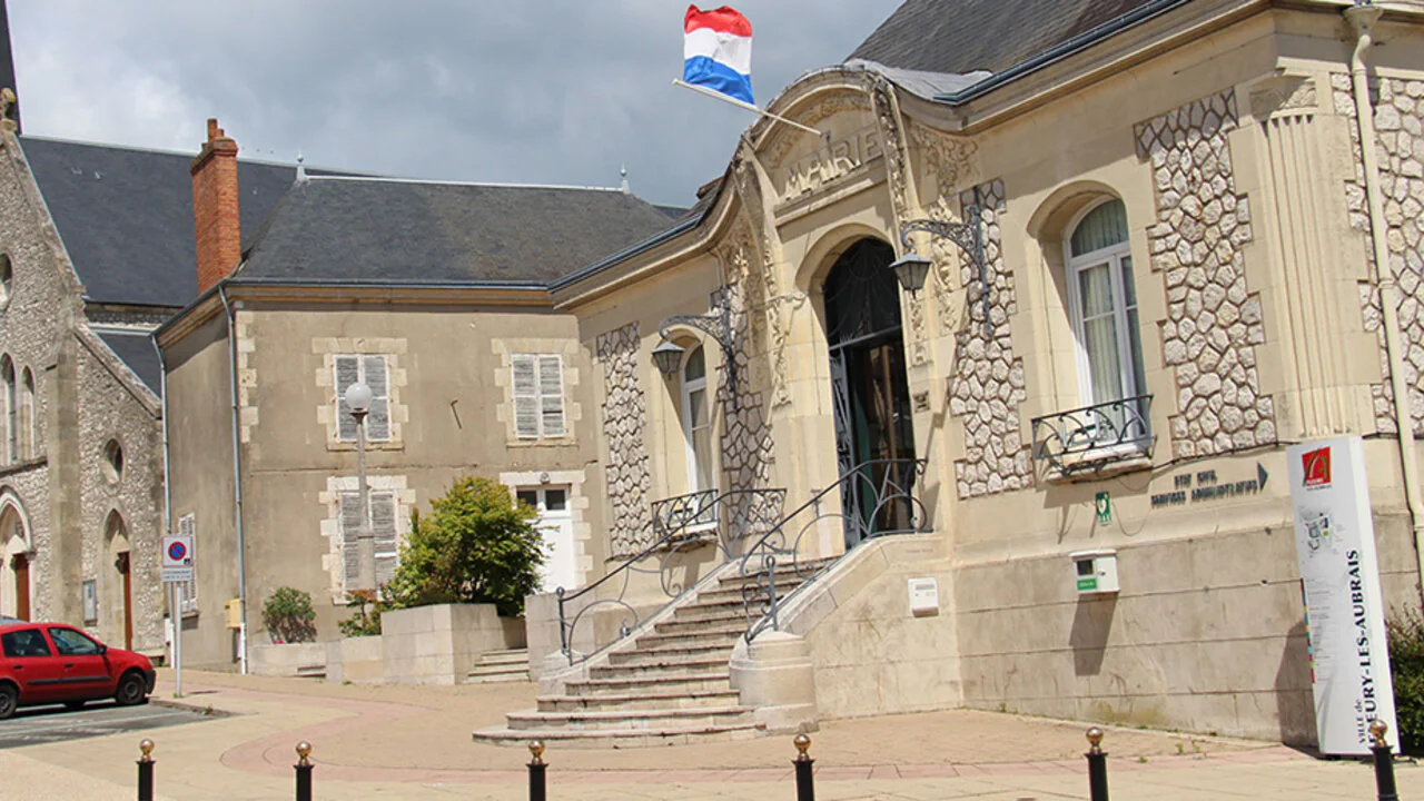 La mairie de Fleury-les-Aubrais, sa façade de pierre ornée et son perron, sous le drapeau français