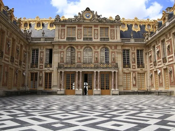 La cour de Marbre du château de Versailles, sa façade de brique et ses balcons dorés