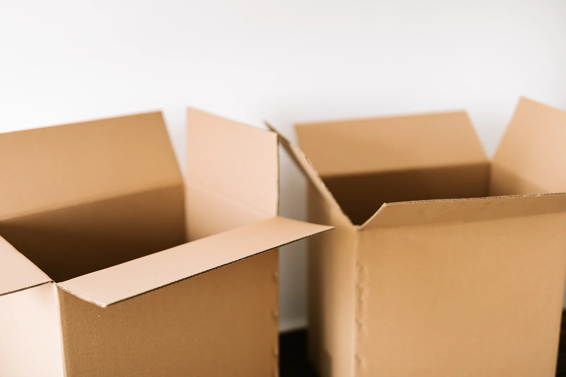 Deux cartons vides aux rabats ouverts, devant un mur blanc