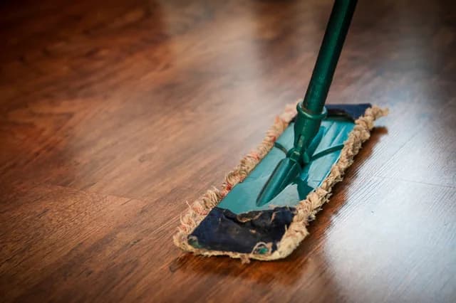 Un balai à franges sur un parquet
