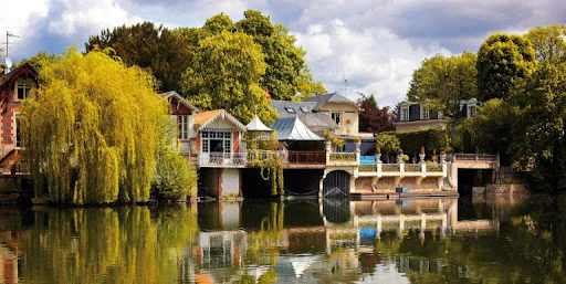 Des maisons au bord du Loiret, à Olivet, et un saule pleureur se reflètent dans l’eau calme