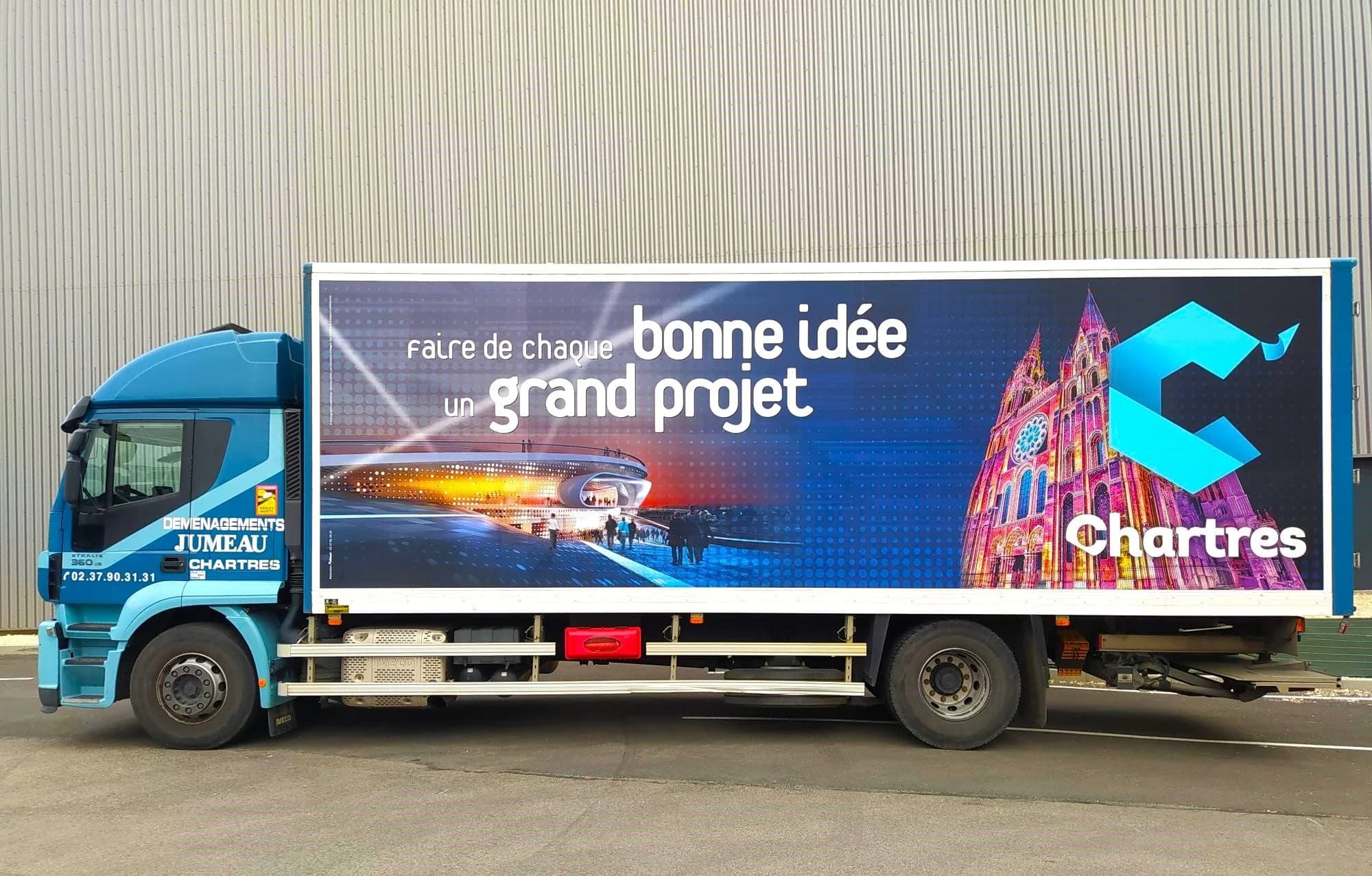 Un camion des Déménagements Jumeau de Chartres habillé d’une affiche « Faire de chaque bonne idée un grand projet » aux couleurs de Chartres