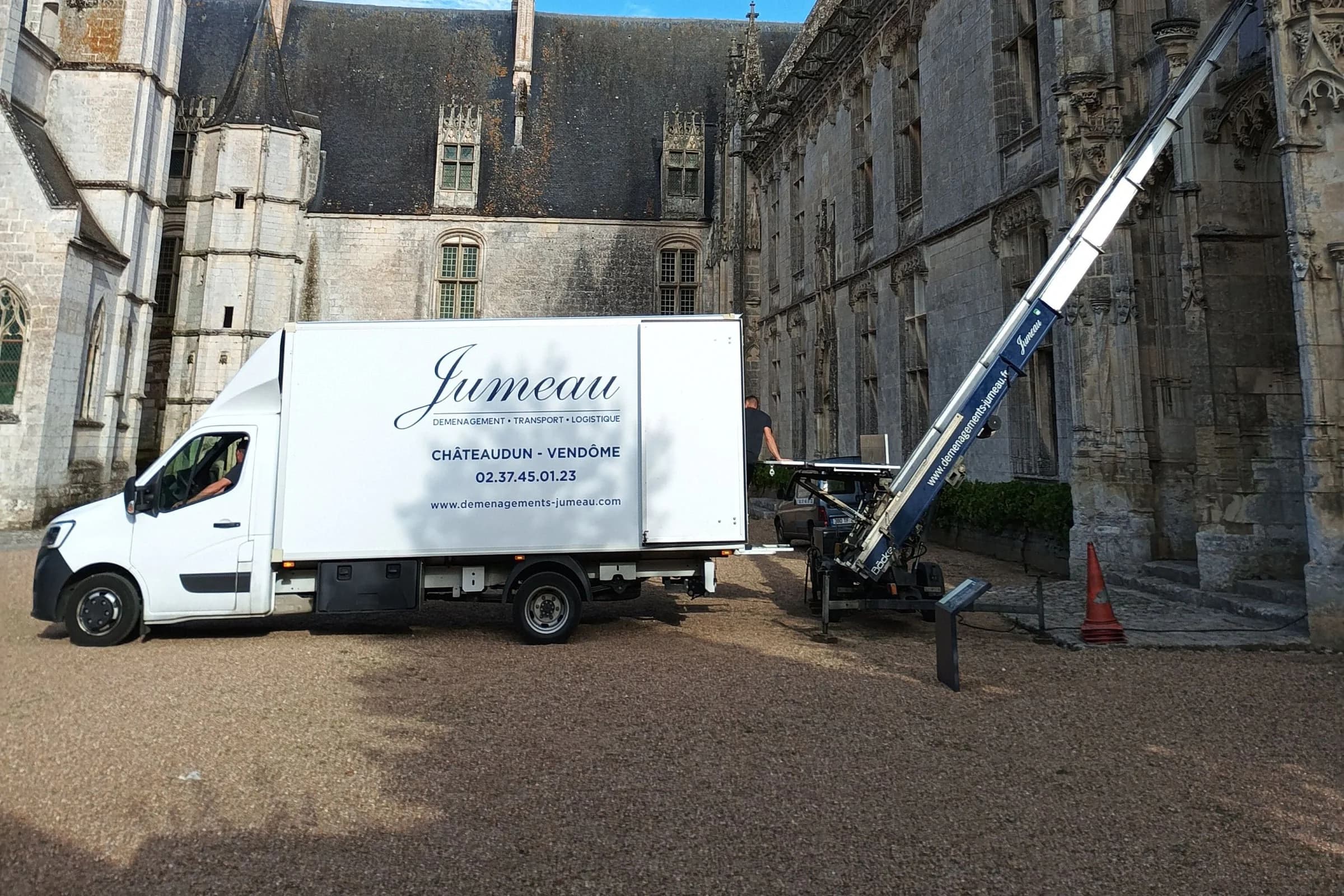 Un camion Jumeau « Châteaudun – Vendôme » et un monte-meubles devant une façade gothique