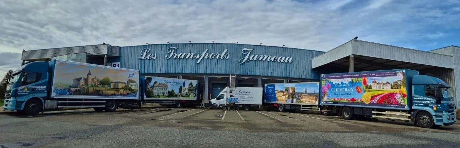 Le bâtiment des Transports Jumeau, des camions habillés de vues de châteaux alignés le long de ses quais